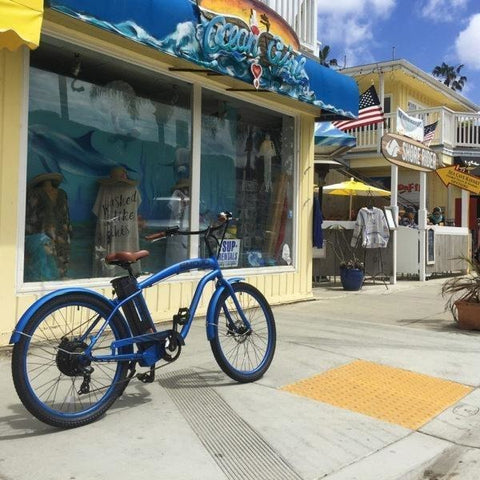 Blue EMOJO Hurricane - Cruiser Electric Bike - In front of a store